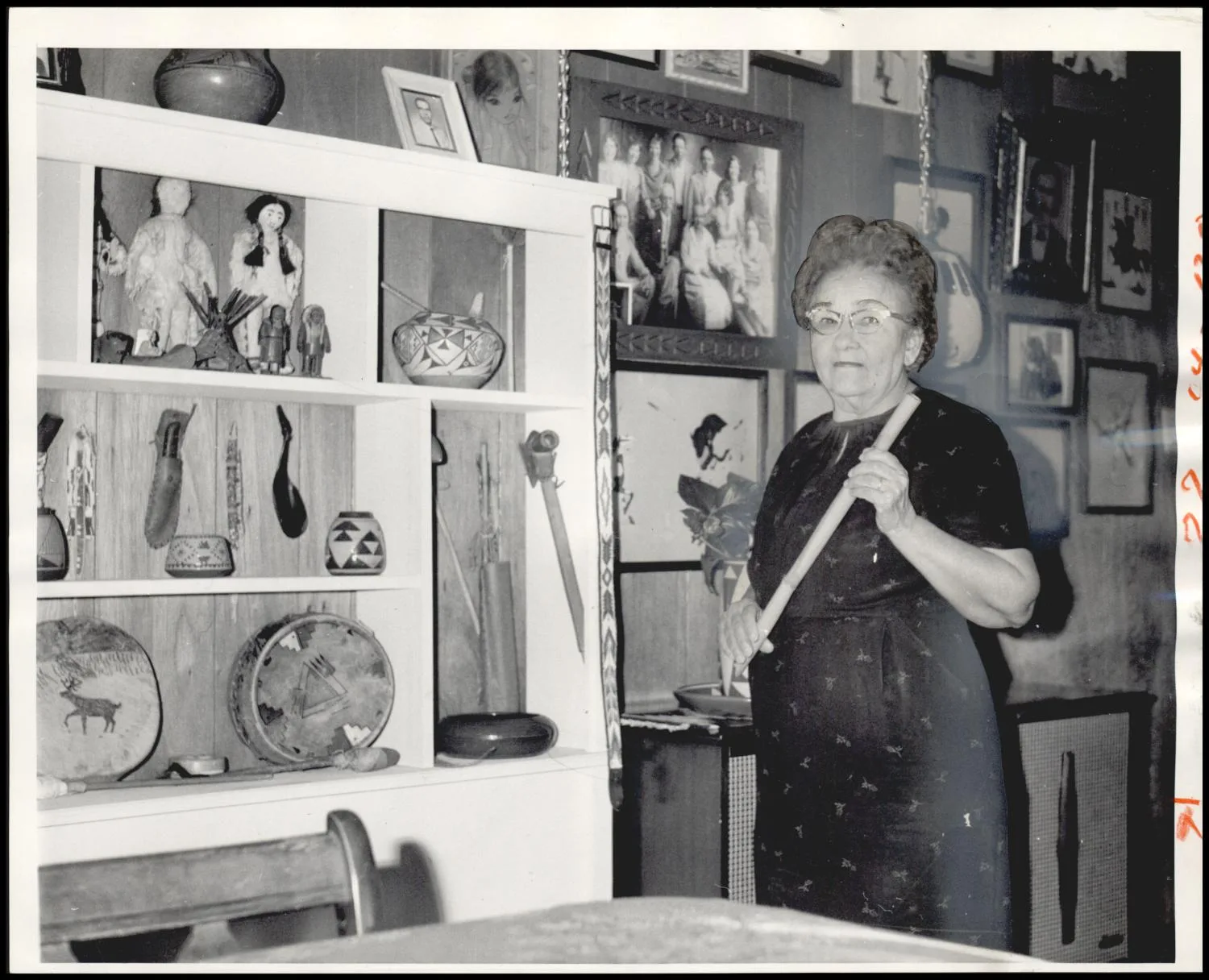 Photograph used for a story in the Oklahoma Times newspaper. Caption: "Mrs. Vivian McGilberry, her vast Indian artifact collection behind her, holds a reed flute on which elder Pueblos played "Indian Love Call" to welcome her and her husband to the Pueblo reservation. (She is half Chickasaw, her husband half Choctaw, and they began their long education careers in the Nickle Hills School north of Tishomingo in 1919.)"